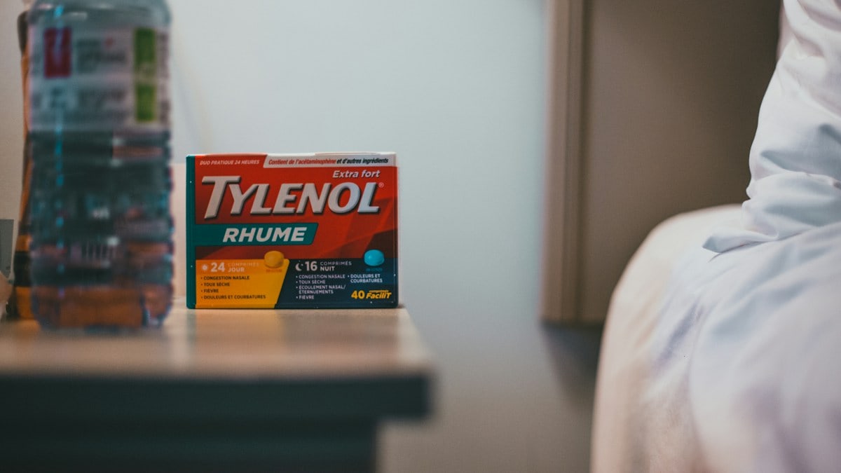 a bottle of tylenol next to a bed